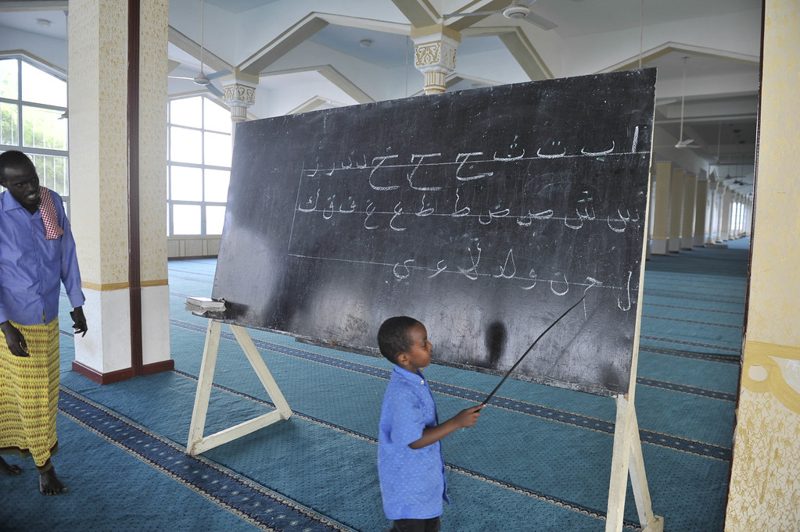 Child learning Arabic letters at a blackboard